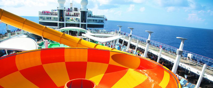Im Vordergrund schlängeln sich die bunten Wasserrutschen des Aqua Parks an Bord der NCL Epic, dahinter laden Pools und Sonnendecks zum Verweilen ein.